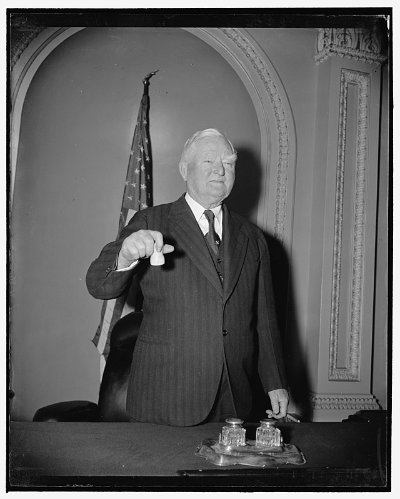 A historical black and white portrait displays an official holding the original U.S. Senate gavel.