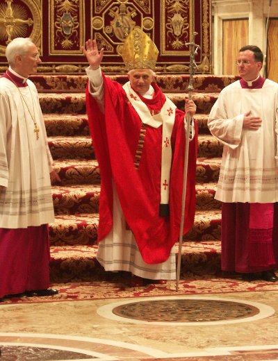 Pope Benedict XVI raises his hand in blessing while holding the original papal crucifix.
