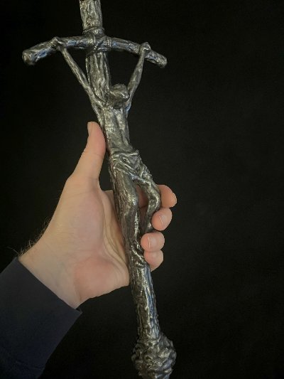 Close-up view of a hand grasping the upper shaft of the crucifix.