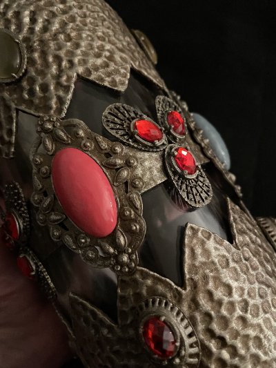 Close-up of a floral motif cluster made of red rhinestones embedded in the textured casing.