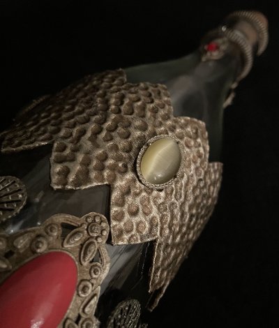 View of the bottle shoulder featuring an amber cabochon set within the hammered metallic overlay.