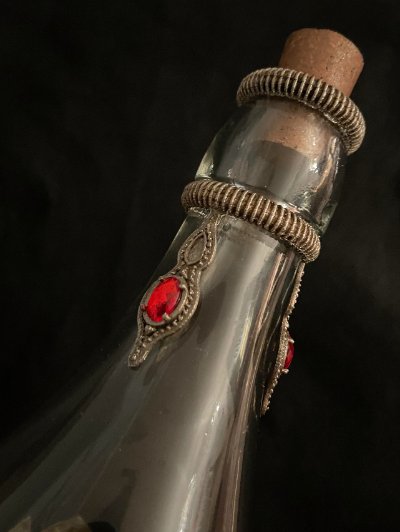 Detail shot of the bottle neck showing ribbed metal rings and a traditional cork stopper.