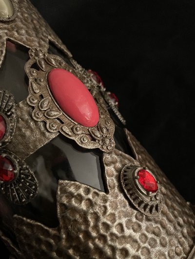 Macro view of the hammered bronze-style casing adorned with large pink and small red stones.