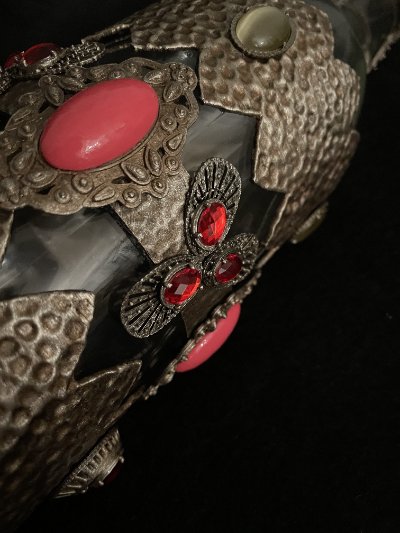Detail showing the transition between the dark glass body and the jeweled metallic overlay.