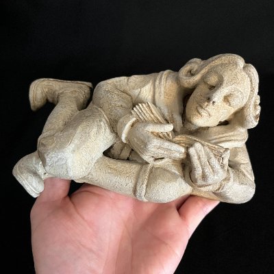 Full limestone scholar replica held in a human hand to demonstrate scale.