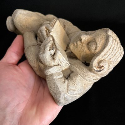 Close-up view of the upper torso and open book held in a hand for scale.