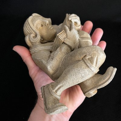Underside and side profile of the scholar sculpture held in a human hand.