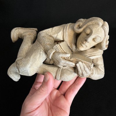 Frontal perspective of the replica scholar resting in a hand for scale reference.