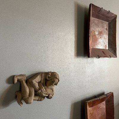 Reconstituted limestone scholar sculpture mounted on a wall as a decorative relief.