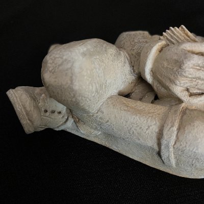 Detail view of the sculpture's lower half, showing carved leg and boot texture.
