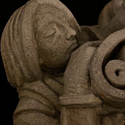Profile close-up of the scholar's face resting near the unfurled stone scroll.