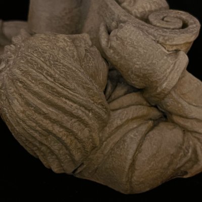 Detailed overhead perspective of the figure's head and hands holding the scroll.