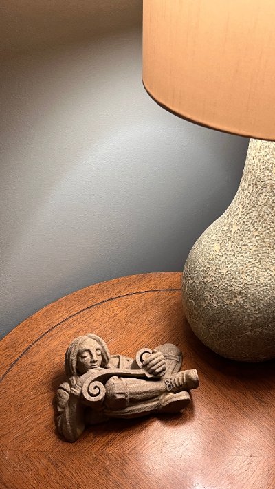 The scroll reader sculpture displayed flat on a wooden table beneath a warm lamp.
