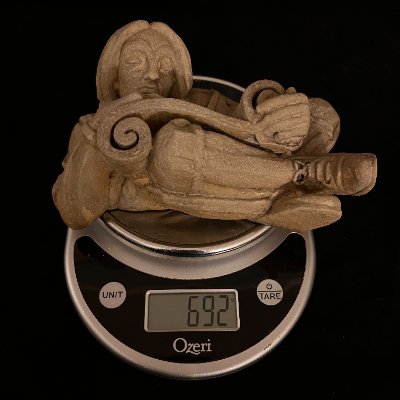 The heavy limestone replica displayed on a digital scale showing a 692-gram weight.