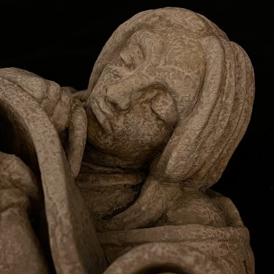 Close-up detail of the gothic scholar's face, showing the textured limestone finish.