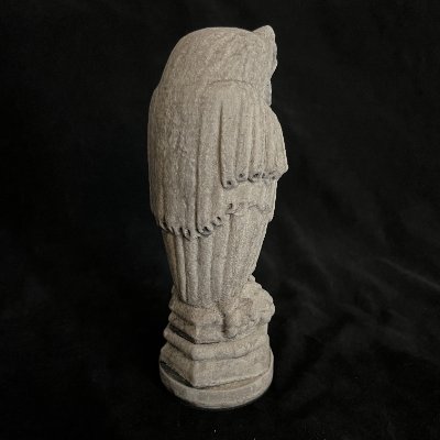 Rear angled profile of the limestone owl sculpture showing the draped Gothic robe details.