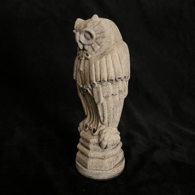 Left angled profile of the Yale Law School owl sculpture resting on a solid pedestal base.